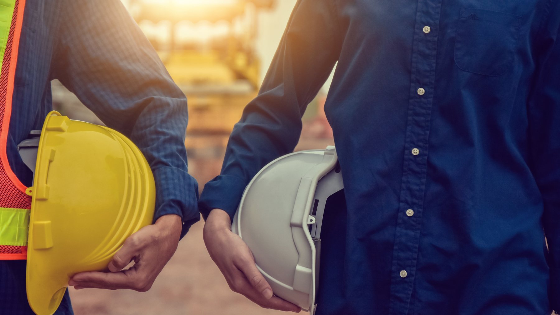 Dois colegas de equipa com capacetes na mão, prontos para colaborar num projeto
